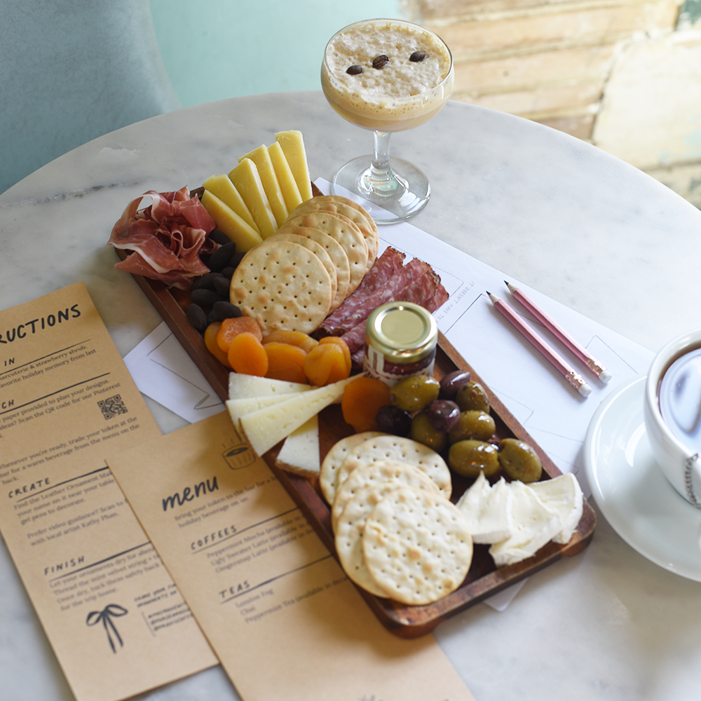 Plated appetizers with a drink on a marble table, accompanied by menus.